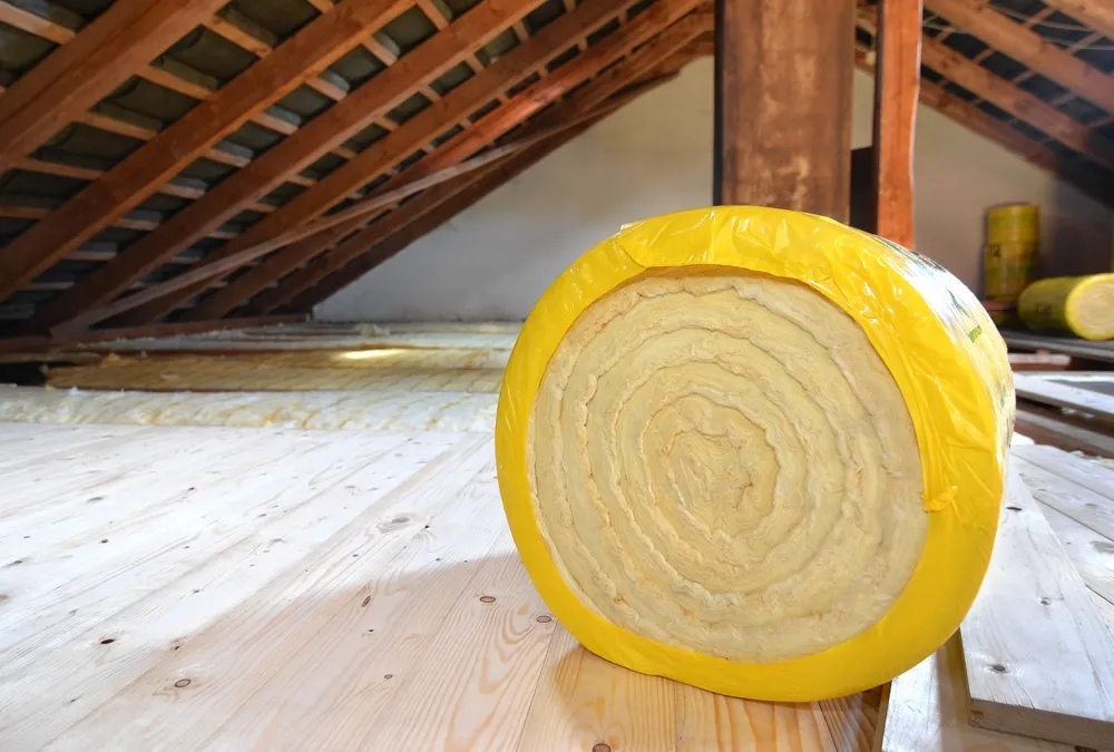 Rol isolatiemateriaal op een houten zoldervloer onder het dak